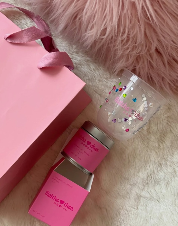 Matcha-chan tin and box beside a pink gift bag and a gem-covered cup